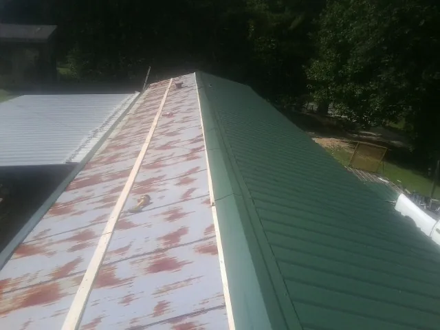 Old rusted panels beside newly installed green metal roofing — Wind Damage Roof Repair by Roofing Brothers in Conover