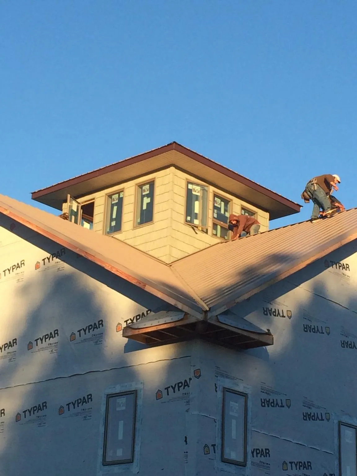 Roofers working around a rooftop cupola on a new metal roof at sunset — Roof Waterproofing in Conover by Roofing Brothers